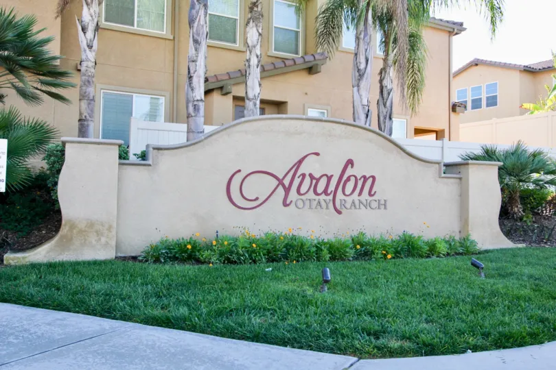 The name of the Avalon condos rests on a sign in a lawn in front of a condo building