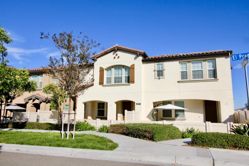 Trees in front Two story white home with hedges & grass located at Avalon in Chula Vista CA
