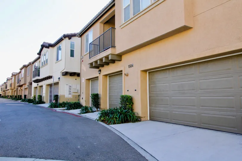A tan-orange duplex complex with a balcony and garage.