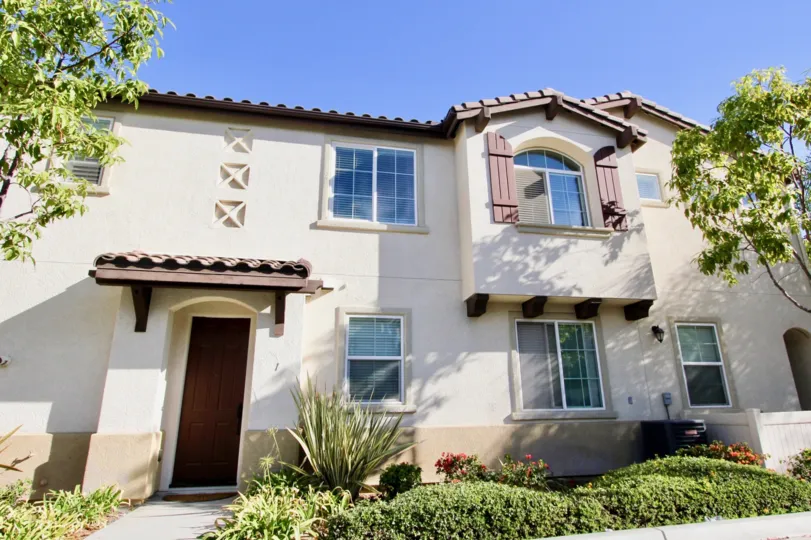 A pink & white town home with a tall brown entrance at Avalon in Chula Vista CA