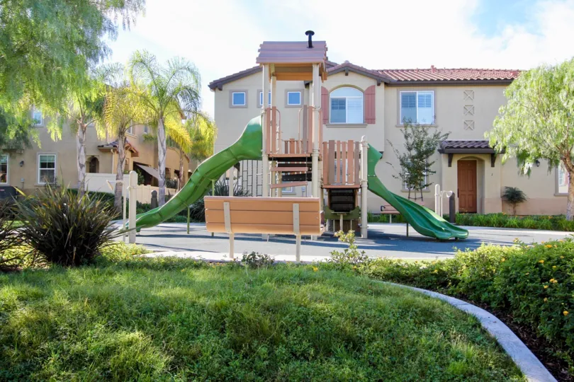 Green wavy slides protrude from a jungle gym at Avalon condos