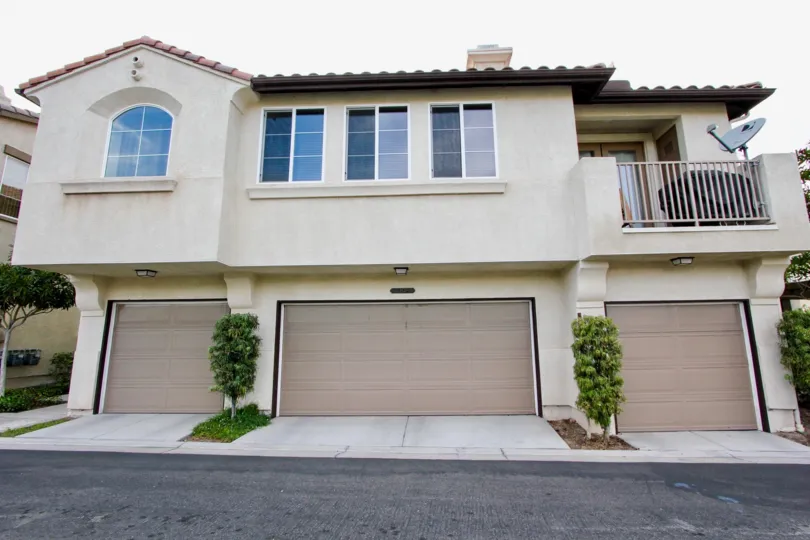 Street view of above-garage apartments with satellite television and grille on upper deck: Chula Vista, CA