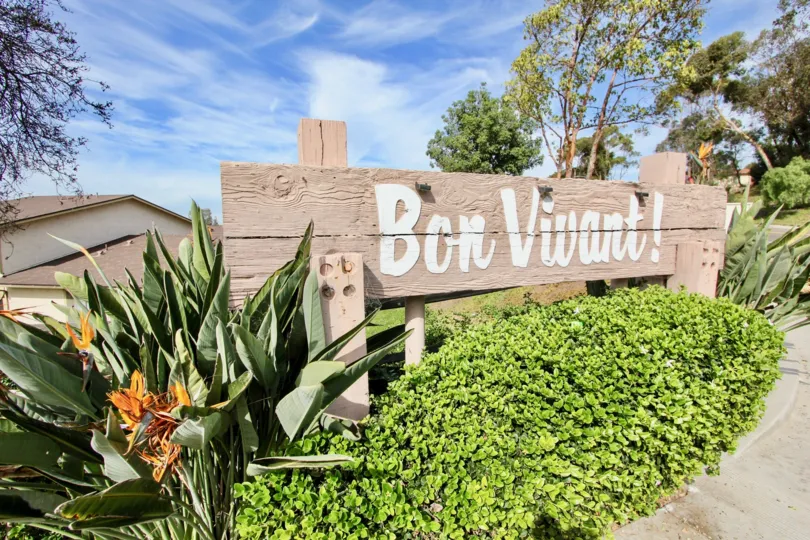 "Bon Vivant" sits on a wooden plank sign near a condo complex in Chula Vista,