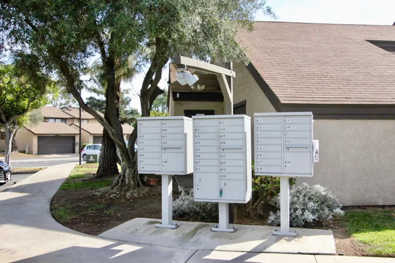Curbside located community mailboxes with large trees and shrubs at Bonita Terrace