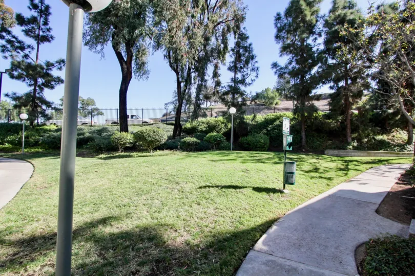 Walking path at Bentwood Arms with pet clean-up station and fence in the distance.