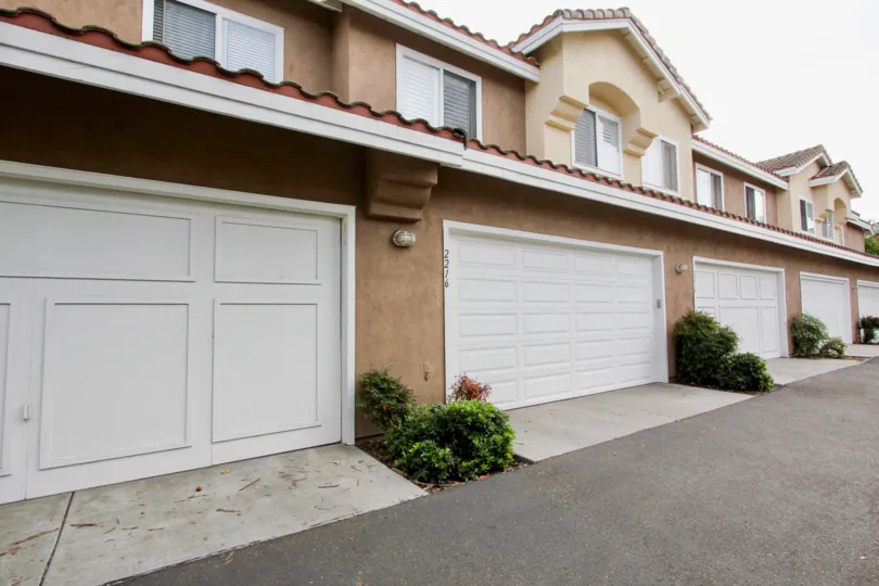 Five white garage doors with plants next to them in Cabo Bahia at Chula Vista CA