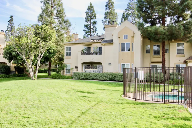 Large green field around a swimming pool with a fence at Camelot in Chula Vista CA