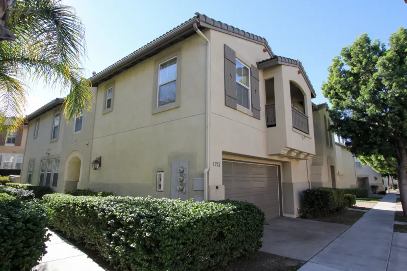 A two story brown home with a long hedge next to it in Chula Vista CA at Capri