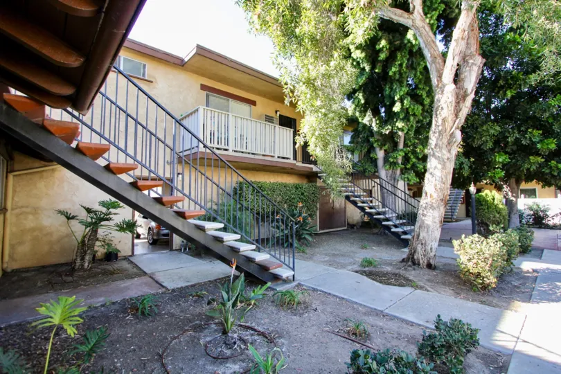 Communal courtyard with gardens and mature trees with concrete slab walkways at Casa de Moss