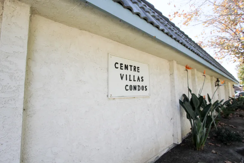 Placard sign for Centre Villas Condos in Chula Vista, CA. Birds of paradise growing alongside.