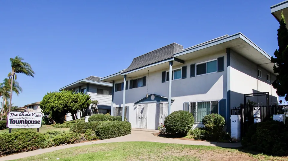 THE BUILDING IN THE CHULA VISTA TOWNHOMES WITH THE GRASSLAND, NOTICE BOARD, PLANTS