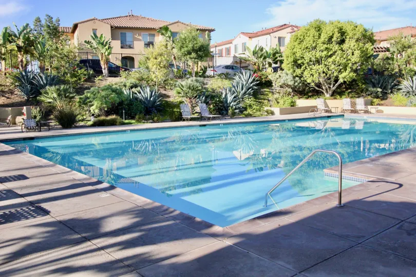 THE APARTMENTS IN THE CORDOVA WITH THE CAR PARKING, SWIMMING POO, TREES, CHAIRS, PLANTS