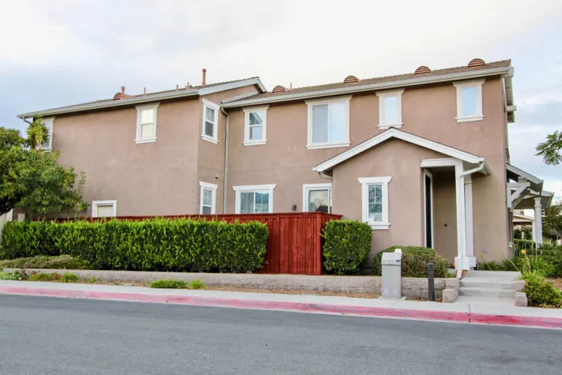 A pink building with lots of windows and a red wooden fence at Cottage Lane in Chula Vista CA