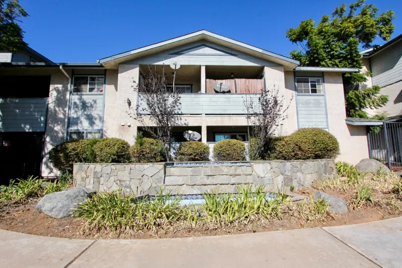 The outside of a gentry Villas home showing the front garden and walkway as well as balcony in Chula Vista
