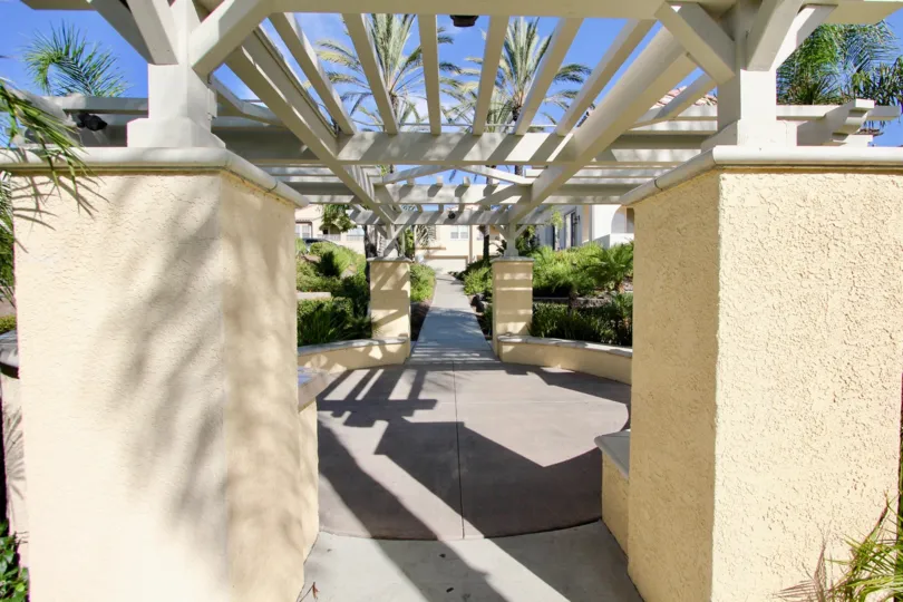 A white wooden pergola casts a shadow on a patio at Gold Rush condos