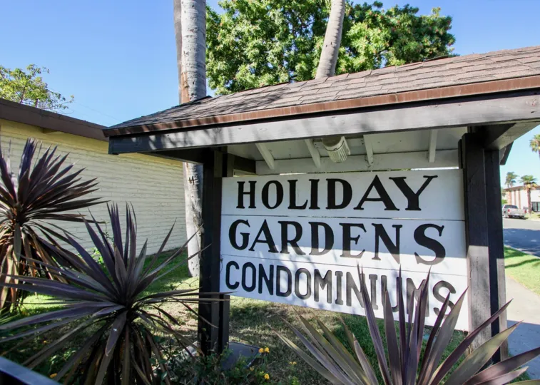 Entry sign to Holiday Gardens Condominiums in Chula Vista, CA on a clear day