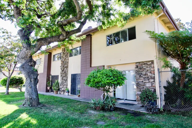 A sunny day in the Holiday Gardens with many types of trees and the house at Chula Vista in California