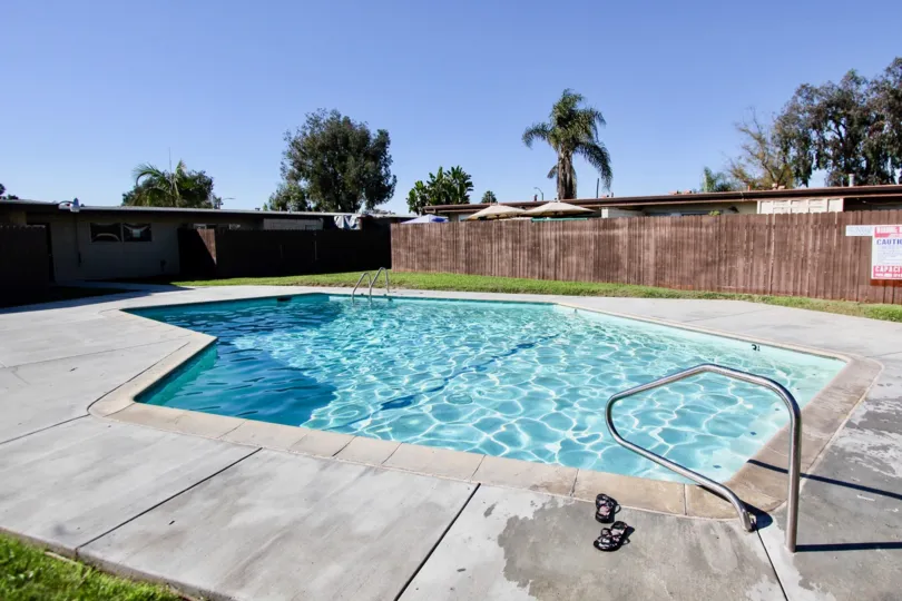 A sunny day at the pool from Karen Condominiums with a fence in the background.