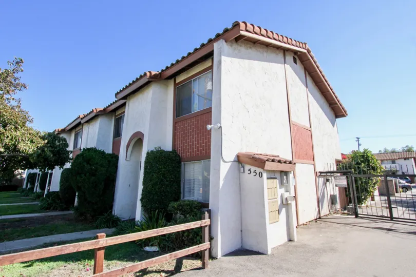 a rather spacious housing with light pink colour walls and small decent windows and a good grassy lawn and tree on it