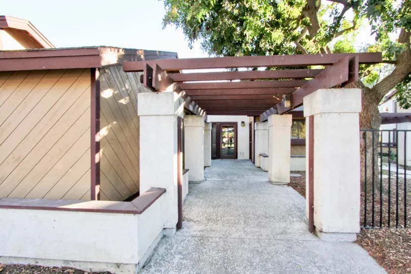 Photo of a paved back walkway to a white and brown building in Melrose Villas community of Chula Vista, California.