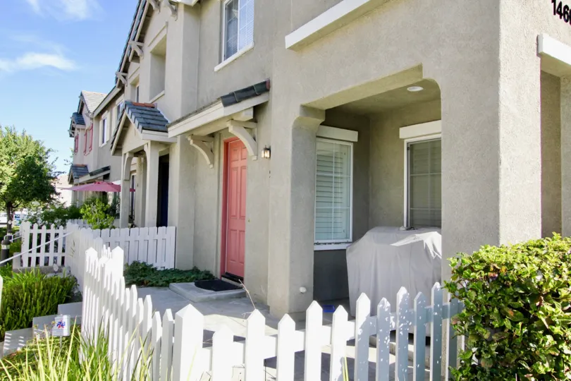 A sunny day in the area of Monet, outside, white picket fence, bush, door, condos