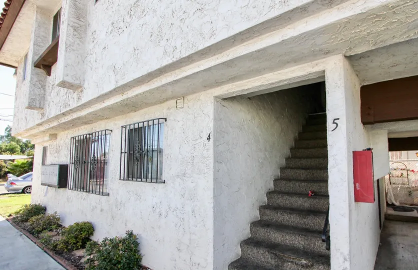 Dark concrete stairs ascend up a dark hallway at Park Way Villas