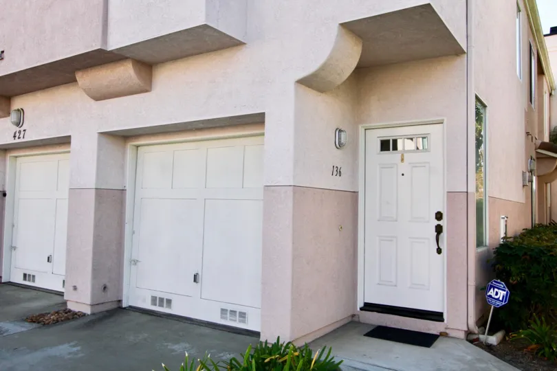 The outside of a Sanibelle home showing the side of the building and two garage doors as well as the entrance to 734 in Chula Vista
