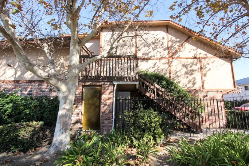 The side view of the beautiful house with the tree and plants, one door and the gate are there in the community of Skyview
