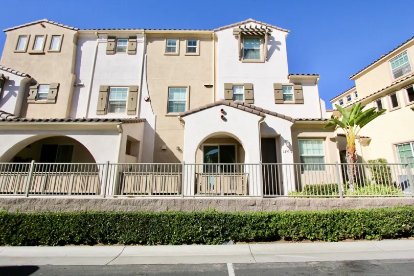 A sunny day in the area of Stetson, iron rod fence, sliding glass doors, bushes, sidewalk, condos, roof