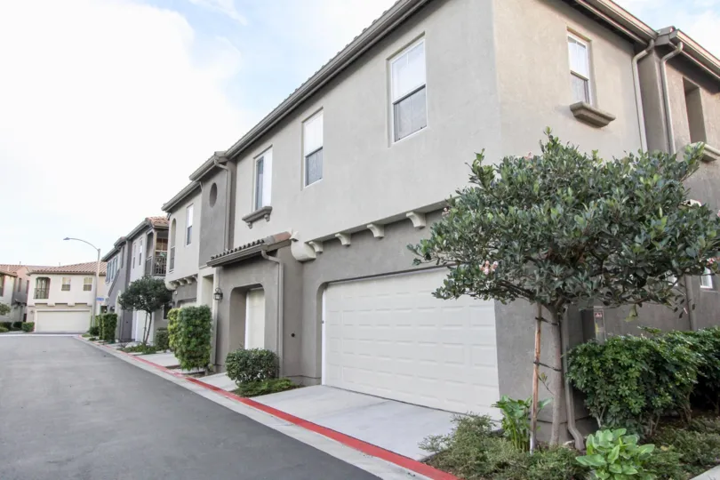 A clear road in front to the garages and front doors of the tidy and peaceful townhomes of Summer Hill in Chula Vista, California.