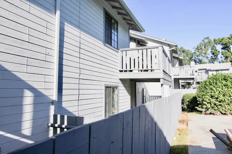 Back of white two story house with windows and patio on top