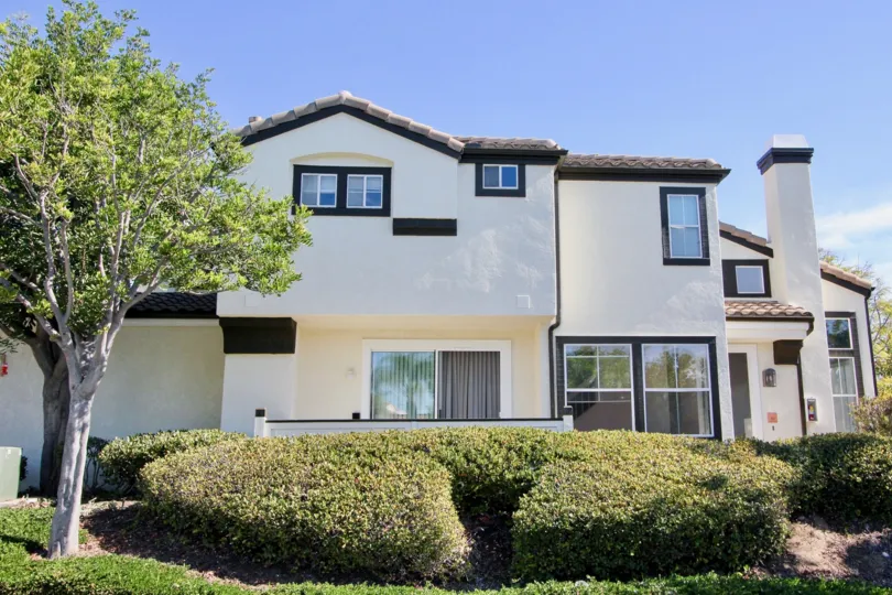 Home with contemporary earthtone colors and well kept shrubs and mature tree in Tiara