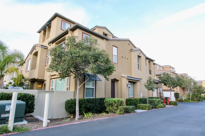A home located in Veranza community in Chula Vista, California. This is a large home with trees and other foliage, showing the street it is located on.
