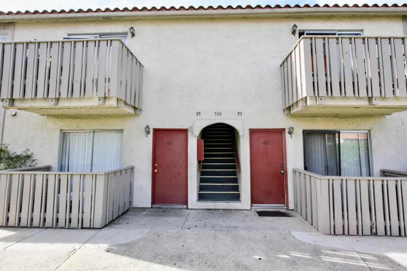 A multi-unit stucco dwelling with red doors and balconies