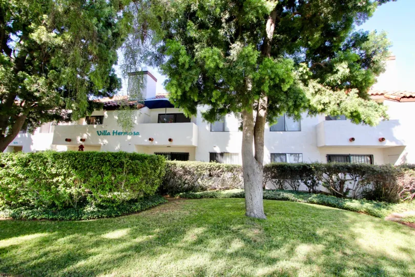 Beautiful lush green lawn with shady trees and neaatly trimmed hedges in front of Villa Hermosa in Chula Vista, California