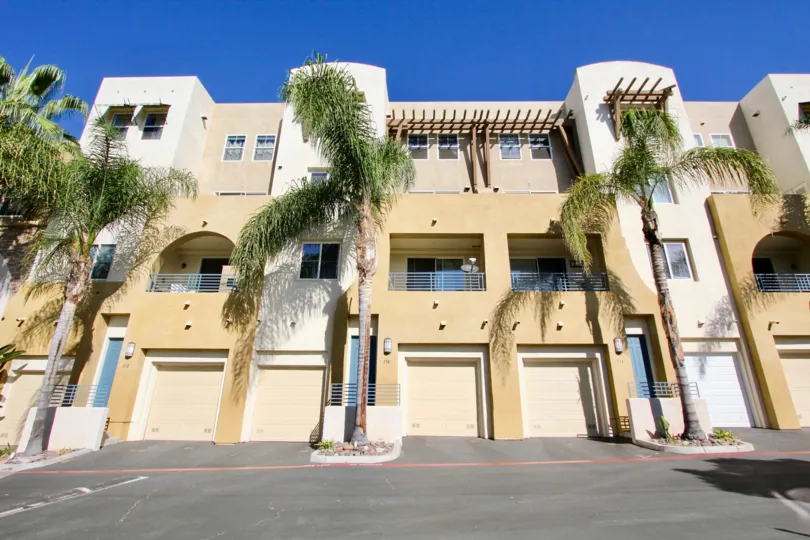 A light brown building in a sunny setting with trees at Villagio.
