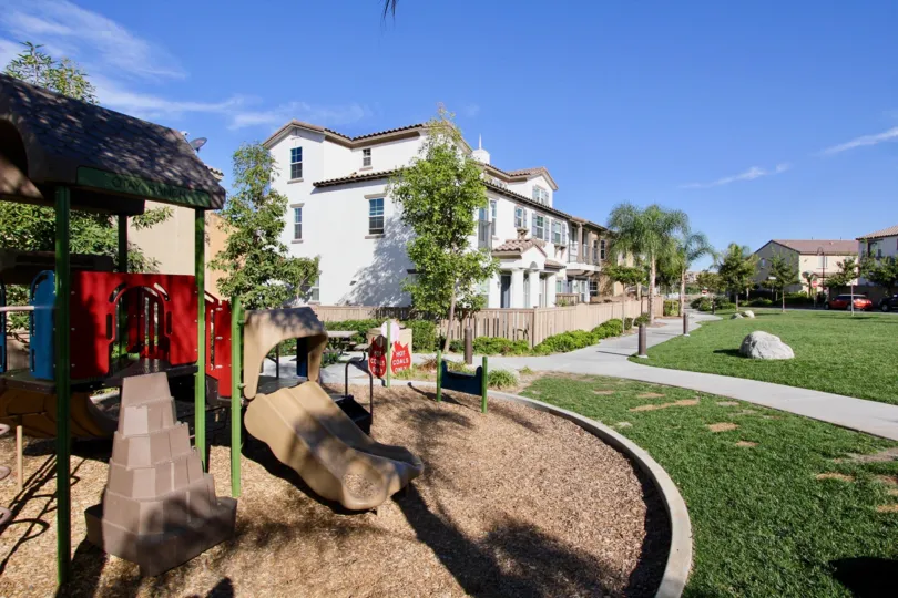 A sunny day in the area of Villas De Avila, park, slide, wooden fence, sidewalk, condos, rock