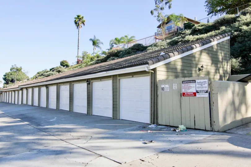 Single car garage units with imposing sloped roof adjacent to garbage disposal shed at Woodland Hills
