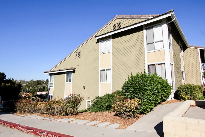A sunny day in Woodland Hills has big bushes and trees at the side of the house