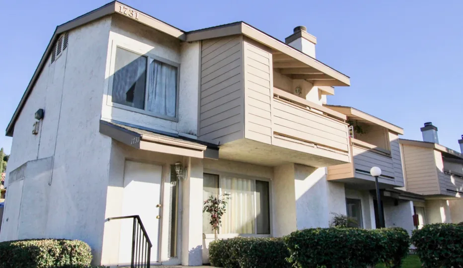 A white building with wooden balconies in a sunny setting.
