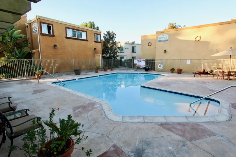A public pool in a Clairemont Mesa California apartment complex. Patio furniture and potted plants are present.
