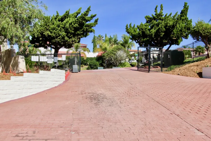 Brick road entrance with black iron gate at Costa Viva in Clairemont Mesa California.