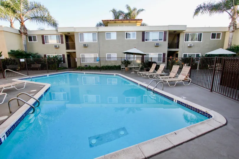 Large blue swimming pool and seating area below residential building at Heritage Park East in Clairemont Mesa California