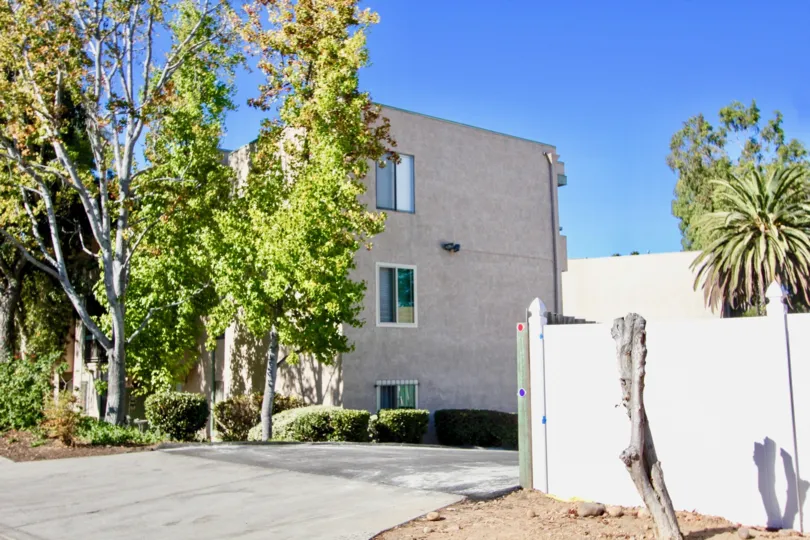 Driveway entrance with tall trees near a three story residential building at Amherst Spring in College Area CA