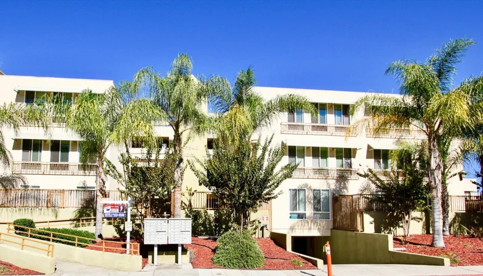 Palm trees and mail box in front of large white residential buildings at Campus Walk in College Area California