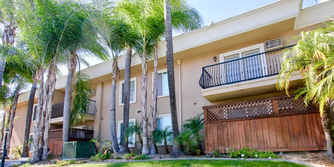 A Carriage House in a College Area in California. 2 Floors, wth balconies and lots of palms trees.