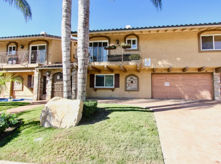 Two story house in City Courtyard College Area, California.  Palm trees and lawn with two car garage attached