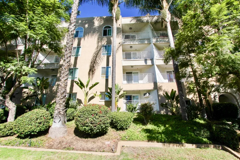 Four storey apartment style condos with tall mature trees and manicured bushes in Parkridge