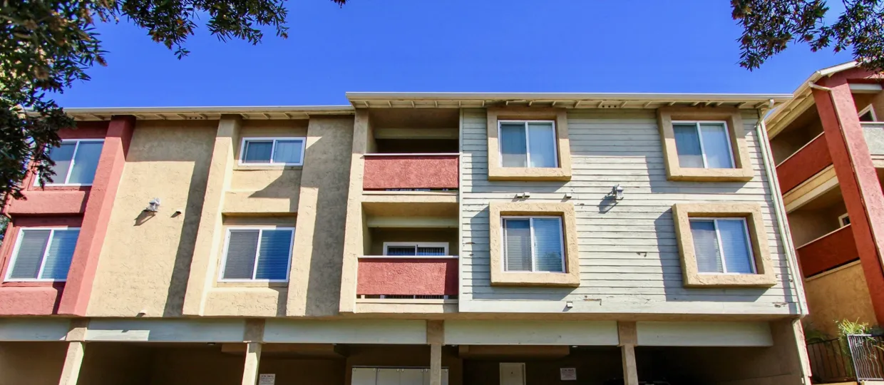 Three story housing with two tall trees inside Saranac Villas in College Area CA