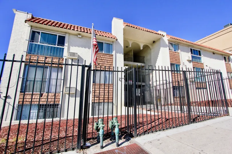 Three story housing units behind a black iron fence at Villa Madrid in College Area California